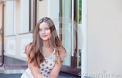 Teen girl with long brunette hair sitting on the marble steps Stock Photo