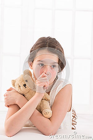 Teen girl lovingly holding a teddy bear sucking Stock Photo