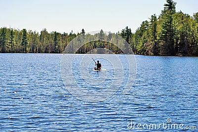 Teen girl paddle boarding in the middle of a lake upper peninsula michigan Stock Photo