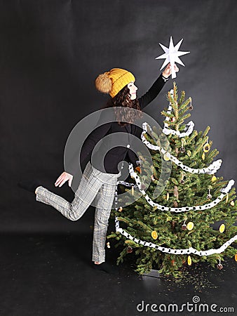 Teen girl putting white paper star on top of Christmas tree Stock Photo