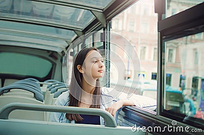 Girl rides a tourist bus and looks out the window. Stock Photo