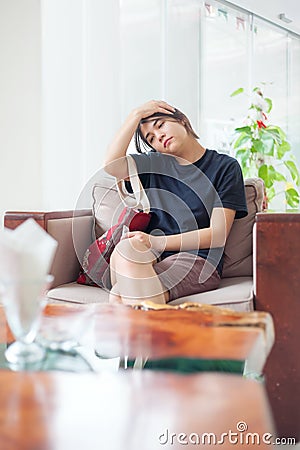 Teen girl sitting in hotel lobby with neckache or heachache Stock Photo