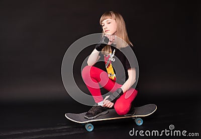 A teen girl with a skateboard on a black background Stock Photo