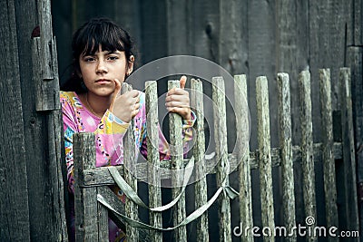 Teen girl standing near vintage rural fence in the village. Stock Photo