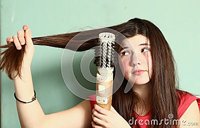 Teen girl straighten her long brown hair Stock Photo