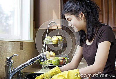 Teen girl washing dishes in kitchen Stock Photo