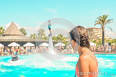 Teen girl watching fly board watershow at the pool. View from the back Stock Photo