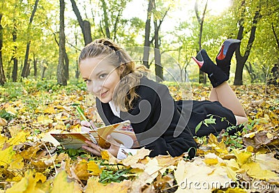 Teen girl writes poetry in copybook in autumn park Stock Photo