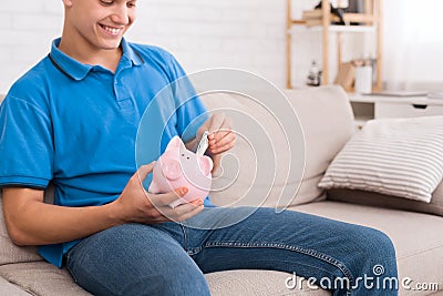 Teen guy saving money with piggy bank Stock Photo