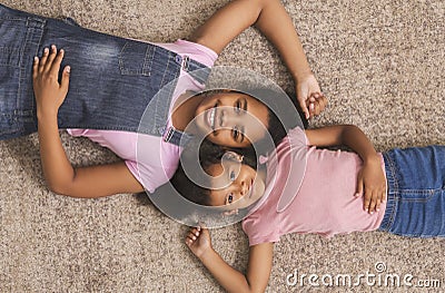 Teen and little african american girls lying together on floor Stock Photo