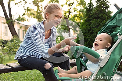 Teen nanny with cute baby in stroller playing Stock Photo