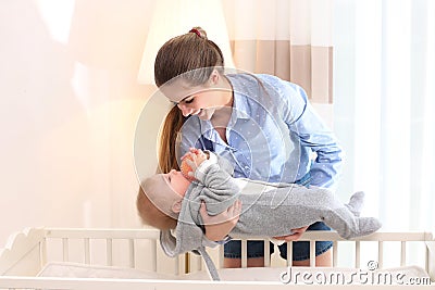 Teen nanny putting cute little baby in crib. Daytime sleep Stock Photo