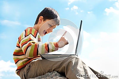 Teen pointing up while playing a laptop outside Stock Photo