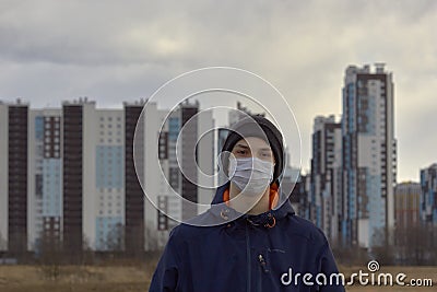 Teen wearing a medical mask against the background of a city against quarantine Stock Photo
