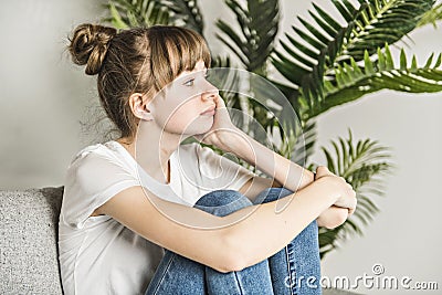 Teen woman anxious worried woman sitting on couch at home. Stock Photo