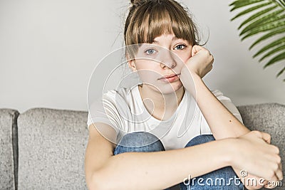 Teen woman anxious worried woman sitting on couch at home. Stock Photo