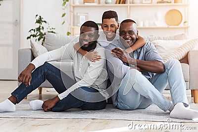 Teenage African Boy, Father And Grandfather Sitting On Floor Posing To Camera Stock Photo