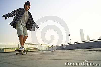 teenage asian boy skateboarding outdoors Stock Photo