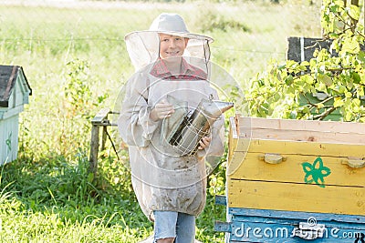 Teenage beekeeper checking hives on bee yard Stock Photo