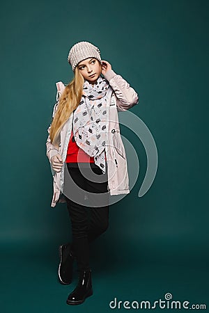 A teenage blonde model girl in modish winter clothes posing over the dark background in full length. Happy girl wearing Stock Photo