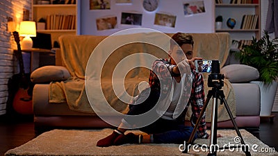 Teenage boy adjusting camera on smartphone for recording videoblog, hobby Stock Photo