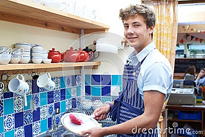 Teenage Boy With Part Time Job Washing Up In Coffee Shop Stock Photo