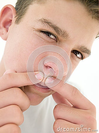 Teenage boy popping zit on face Stock Photo