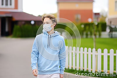 Teenage boy put on face mask because the second wave of covid-19 epidemic began. Lockdown. Mask is new standard for protection and Stock Photo