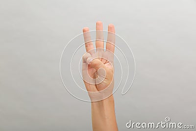 Teenage boy showing three fingers on light background, closeup Stock Photo