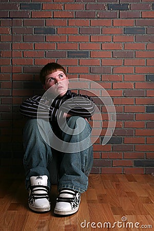 Teenage boy sitting on floor with arms on knees Stock Photo