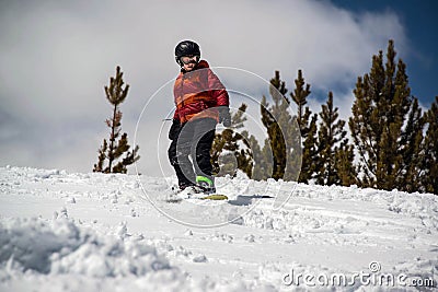 Teenage Boy snowboarding down steep snowy hill in the mountains Stock Photo