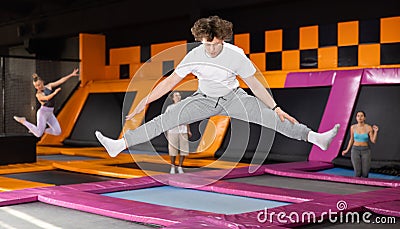 Teenage boy in sport clothes high jumping in trampoline arena Stock Photo