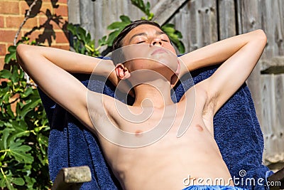 Teenage boy sunbathing in the garden Stock Photo