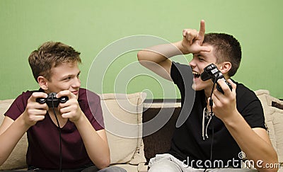 Teenage boy teasing younger brother while playing video games Stock Photo