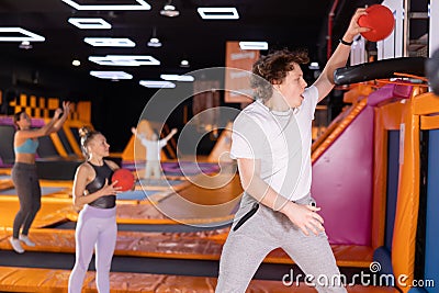 Teenage boy throwing ball in basket high jumping in trampoline arena Stock Photo