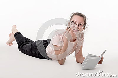 Teenage caucasian girl with glasses is lying and reading book on white background Stock Photo
