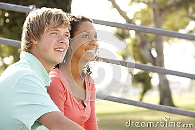 Teenage Couple Sitting In Playground Stock Photo