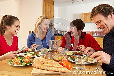 Teenage Family Eating Lunch Together In Kitchen Stock Photo