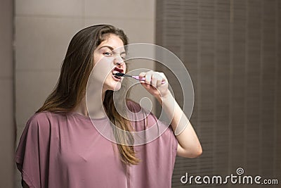 Teenage Girl with Braces Brushing Her Teeth in Front of a Mirror Stock Photo