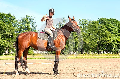 Teenage girl equestrian showing ok sign. Vibrant summertime outdoors Stock Photo