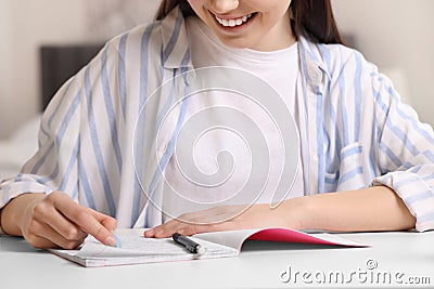 Teenage girl erasing mistake in her notebook at white desk indoors, closeup Stock Photo