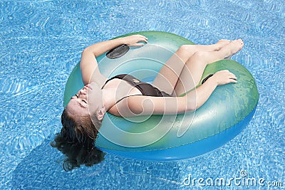 Teenage girl floating in tube in pool Stock Photo