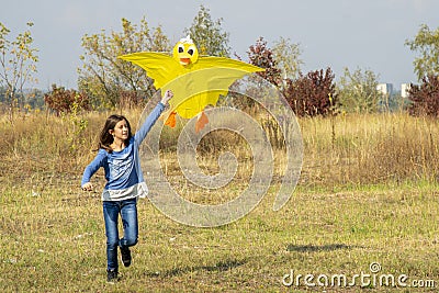 Teenage girl flying a yellow kite. Beautiful young girl kite fly. Happy little girl running with kite in hands on the beautiful Stock Photo