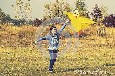 Teenage girl flying a yellow kite. Beautiful young girl kite fly. Happy little girl running with kite in hands on the Stock Photo