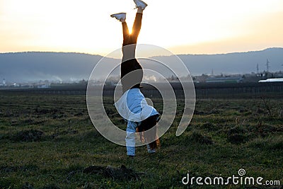 Teenage girl Handstanding on a field in late winter afternoon Stock Photo