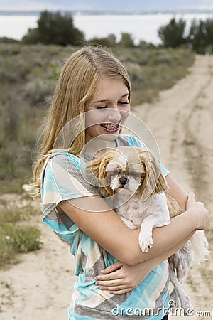 Teenage girl holding dog walking on a dirt road Stock Photo