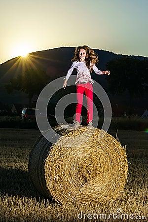 Teenage girl jumping from the haystack Stock Photo