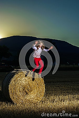 Teenage girl jumping from the haystack Stock Photo