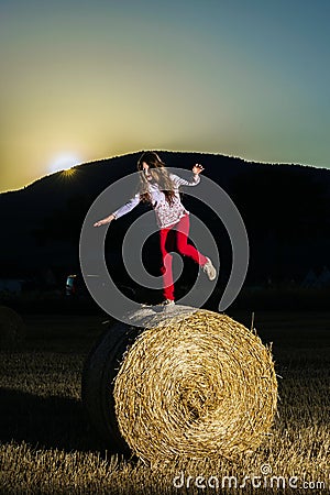 Teenage girl jumping from the haystack Stock Photo