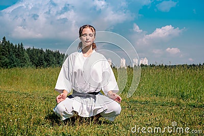 Teenage girl karateka before starting training outdoor enters the mokuso meditative state in the seiza pose Stock Photo